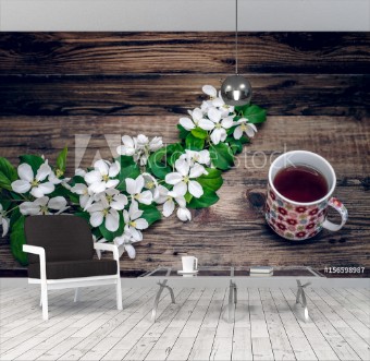 Picture of A branch of apple blossoms and a mug of tea on wooden background